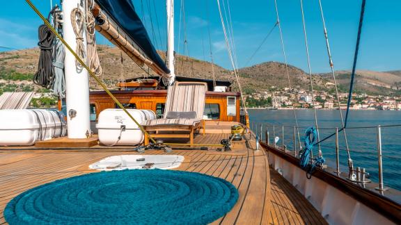 The deck of the Gulet Smart Spirit with a cosy sunbathing area overlooking the coast of Croatia.