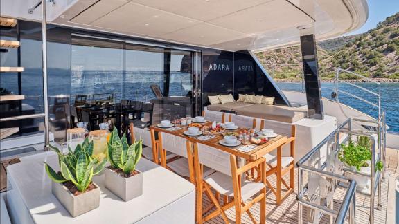 The aft deck of Adara yacht features a stylish dining table and comfortable seating with sea views.