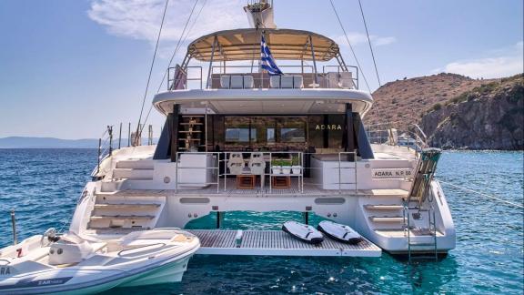 The rear of Adara yacht features a cozy seating area, stairs, and easy access to the sea.