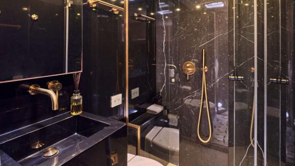 Modern bathroom with black marble details and golden fixtures, combining comfort and elegance.