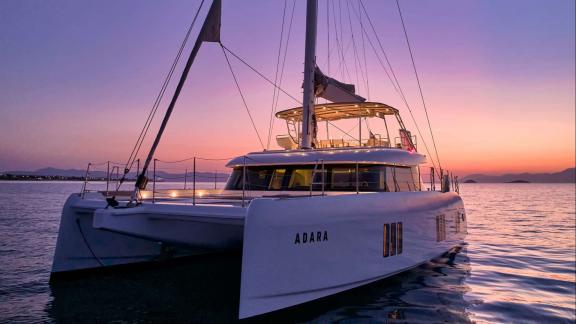 Adara yacht is seen peacefully on the sea under the enchanting colors of the sunset.