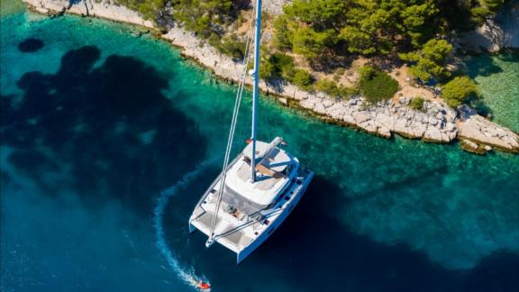 Anchored in the clear waters of Kastela, Sunreef 50 Solitaire offers serene views of the rocky coastline and lush forest