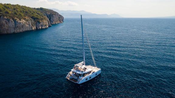 The Sunreef 50 catamaran Solitaire is anchored in a pristine bay surrounded by pine trees near Kaštela.