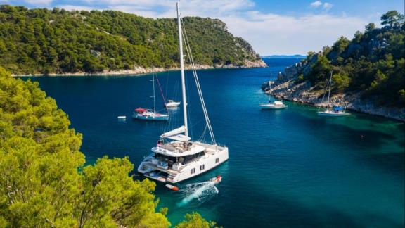 Sunreef 50 Solitaire is anchored in a calm bay near Kastela, surrounded by nature.