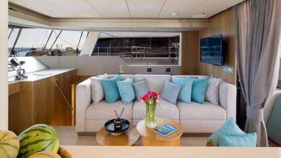 In Kastela Zara’s saloon has a soft couch colorful pillows small tables and a wall mounted TV.