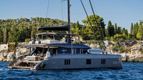 Ahalya charter Sunreef 60 catamaran stands out near Kastela’s scenic shoreline.
