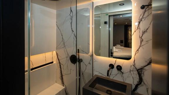 The bathroom of Sunreef 60 Mr. Si features black fittings and marble surfaces for a clean and elegant design.