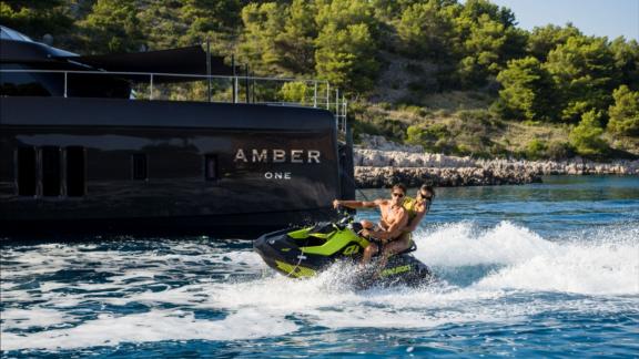 A couple rides a jet ski near the Amber One Sunreef 70 catamaran in Kastela bay.