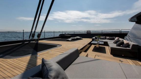 Elegant deck of the Sunreef Catamaran with lounge area and hot tub, view of the open sea.