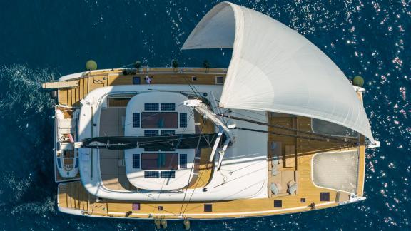 The spacious Honeybird catamaran with wide deck sails under the sun off Šibenik, available for charter.