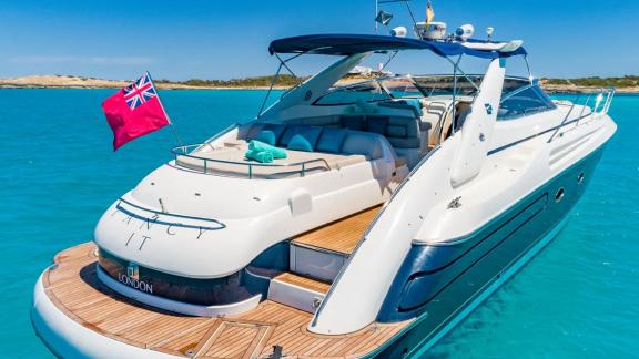 The anchored yacht in Ibiza features a cushioned aft lounge area with turquoise towels.