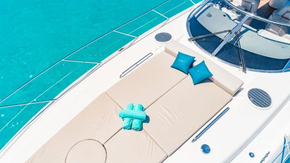 On the foredeck of the anchored yacht in Ibiza lie turquoise towels and pillows.