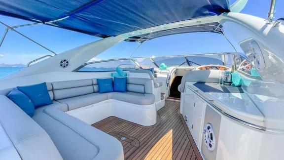 Anchored in Ibiza, the Fancy It yacht offers a shaded seating space with plush cushions for comfort.