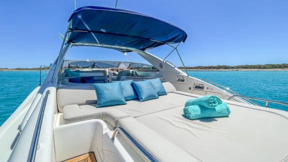 Anchored off Ibiza, the yacht's aft deck features a spacious sunbed with pillows and folded towels.