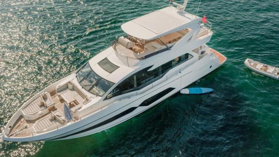 Lady M motor yacht is anchored off Mallorca with a paddleboard and tender nearby.