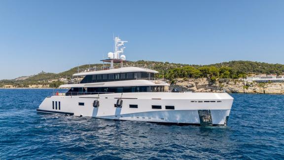 Die Yacht liegt nahe der Küste, mit großzügigen Decks und großen Fenstern.