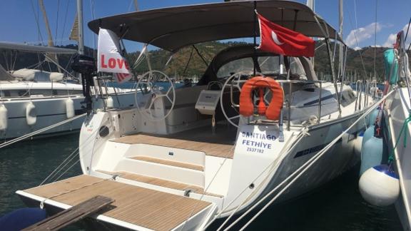 Aft deck of the sailing yacht Santiago docked at the marina with flag and steering wheels visible.