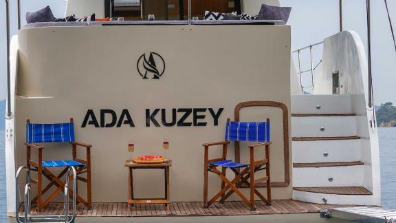 On the swim platform of motor yacht Ada Kuzey, there are chairs and a table for guests to enjoy their time.