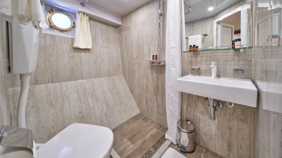 Modernes Badezimmer mit Dusche, WC und Bullauge auf einer 9-Kabinen-Gulet aus Split.