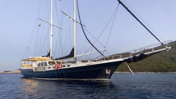 Elegant two-masted sailing yacht The Blue Sea on calm water, photographed from the side.