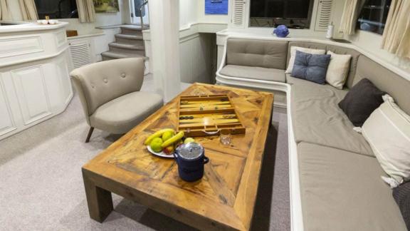 Living area of the sailing yacht The Blue Sea with large wooden table and cosy seating.