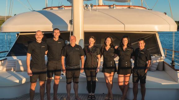 Дружелюбный экипаж моторной яхты Son de Mar позирует на палубе на фоне живописного побережья Сплита.