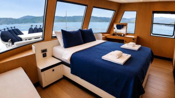The master cabin of Beluga 1 in Göcek features a large bed and panoramic sea views through wide windows.