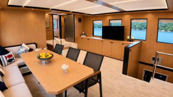 The salon of Beluga 1 in Göcek features a large dining table, lounge seating and a TV unit.
