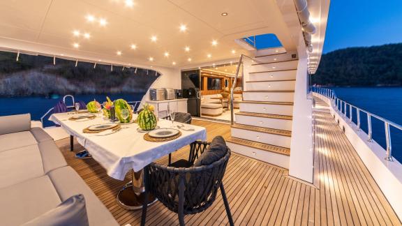 The dining area and stairs leading to the interior of Floki trawler yacht create an elegant ambiance.