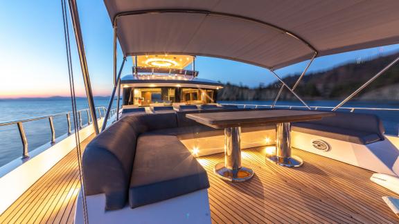 Spacious and comfortable seating area on the deck of Floki trawler yacht with an evening view.