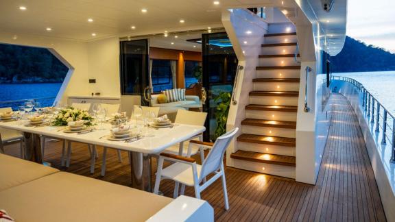 Elegant dinner table and lit staircase on the open deck of Lila trawler near Fethiye.
