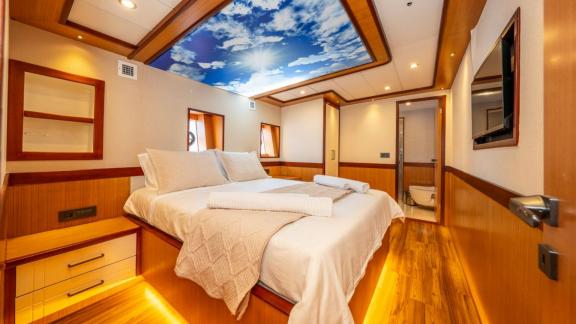 Large bed and sky-themed illuminated ceiling in Lila yacht cabin near Fethiye.