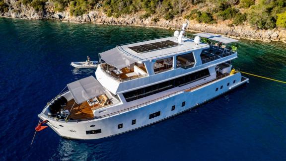 Lila trawler yacht rests at anchor in peaceful bay near Fethiye with spacious decks.