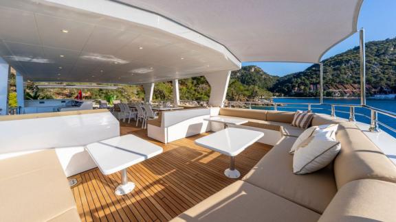 Comfortable sofas and dining tables on upper deck of Lila trawler yacht in Fethiye.