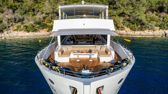 Comfortable sofas and dining table on bow deck of Lila trawler yacht in Fethiye bay.