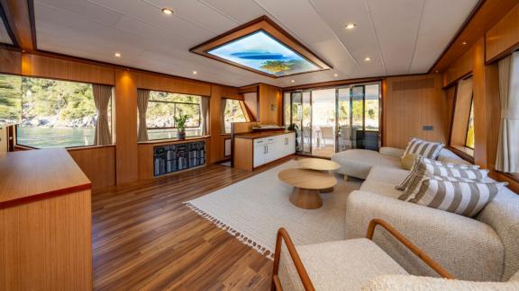 Large salon with sofas and natural wood decor aboard Lila yacht near Fethiye.