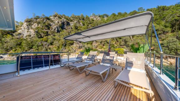 Multiple sunbeds and canopy shade on the upper deck of Lila yacht in Fethiye bay.