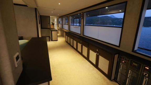 Wide corridor of the trawler Nayk 3 equipped with cabinets and scenic windows.