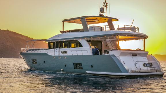 Rückansicht der Trawler-Yacht Floki bei Sonnenuntergang, die eine ruhige Landschaft bietet.