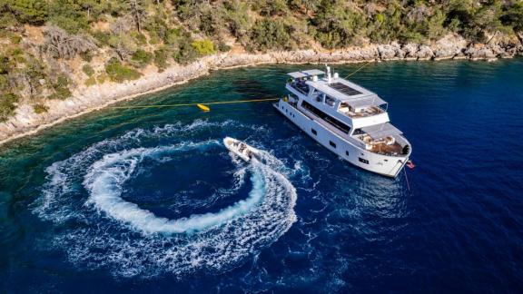 Lila trawler is anchored calmly while motor boat circles nearby in Fethiye bay.