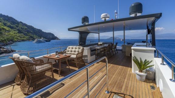 The flybridge of Oggusto yacht features a lounge and bar with bay views.