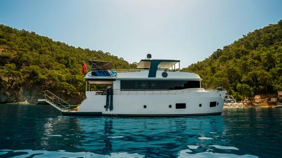 The Oggusto yacht is anchored peacefully in a forest-lined bay of Fethiye.