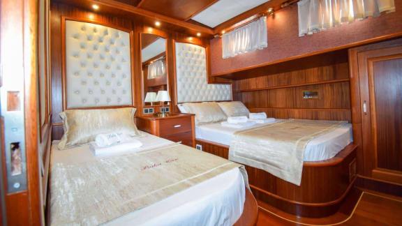 Comfortable cabin with two elegant beds and stylish wood paneling on the Gulet Baba Can.