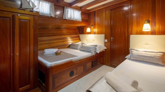 Comfortable cabin on the Gulet Andi Star with two beds and stylish wooden furnishings.