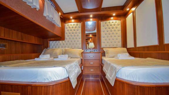 Luxurious cabin with two large beds and stylish wood paneling on the Gulet Baba Can.