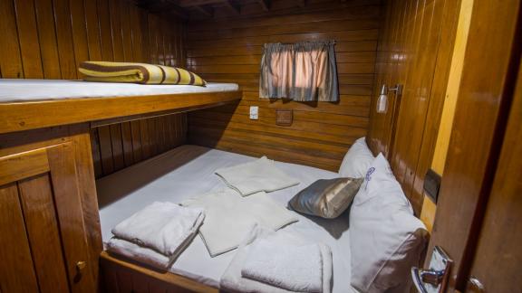 Cozy cabin on Gulet Valerie with wooden walls, double and single bed.