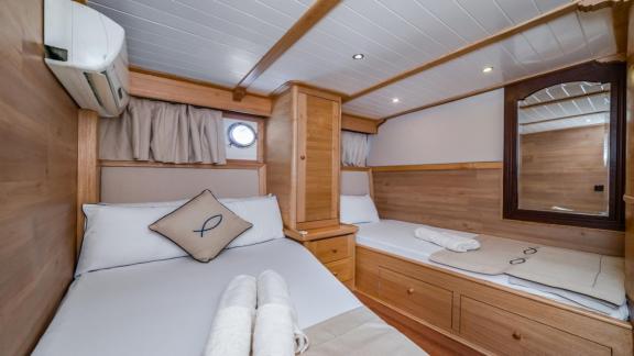 A cosy bedroom on the gulet yacht Amazon Solo with two single beds and wooden furniture.