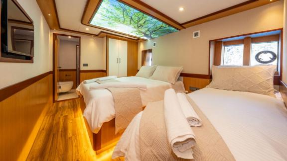 Cabin with two beds and nature-themed ceiling decor in Lila yacht near Fethiye.
