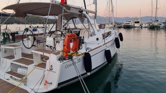 Triton 89 sailing yacht docked at the marina, featuring a wooden deck and spacious seating areas