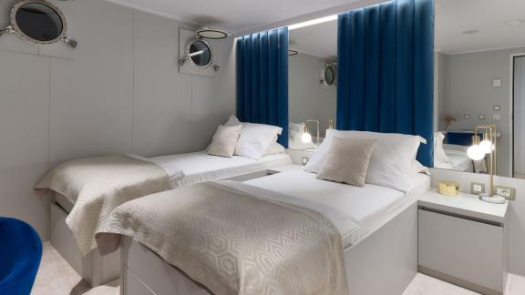 Moderne Zweibett-Kabine der Bellezza Yacht mit gemütlichen Betten und eleganter Beleuchtung.